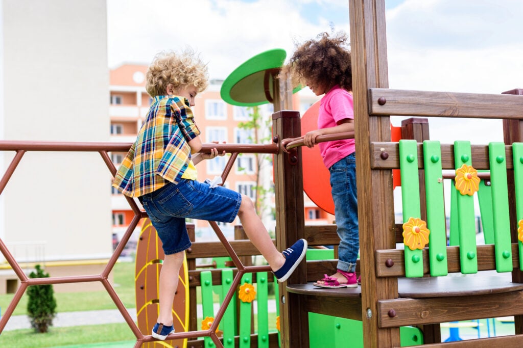 curly multiethnic little children climbing and having fun at playground