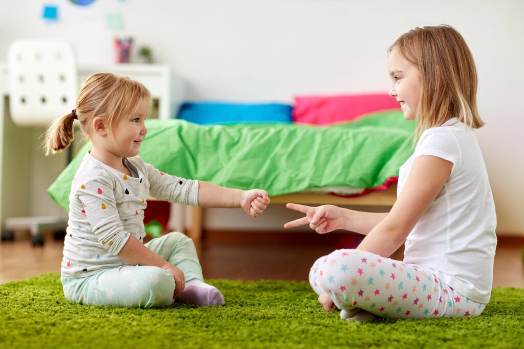 girls playing rock-paper-scissors game at home