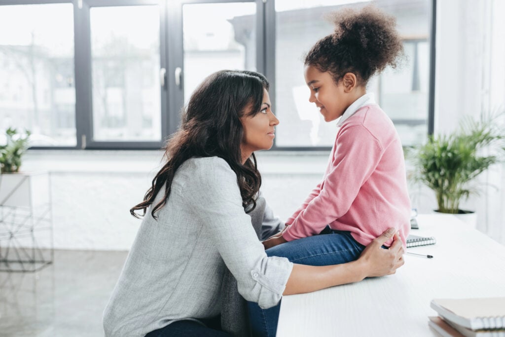 Mother talking to her daughter quietly and politely at home.
