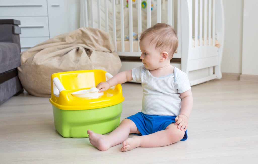 Adorable toddler boy looking at toilet baby pot