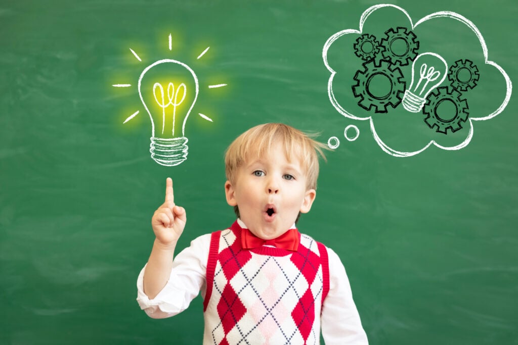 Bright idea! Surprised child student pointing finger up! Happy kid against green chalkboard. Online education and e-learning concept. Back to school