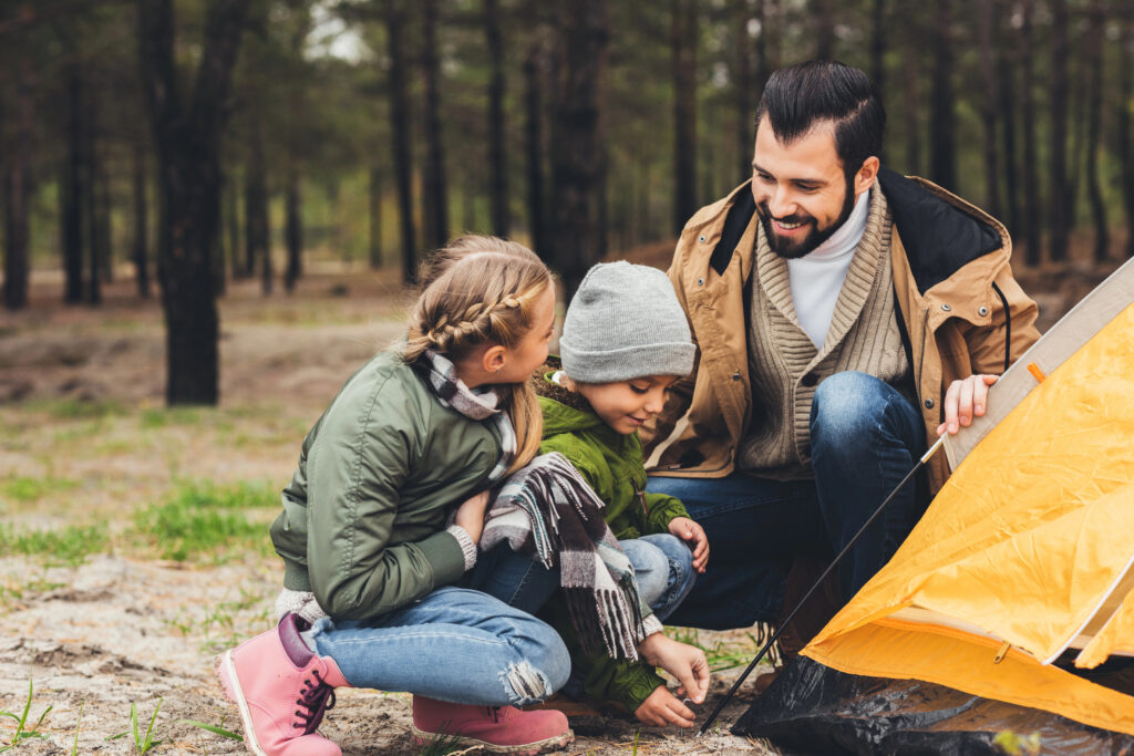 father and kids installing camping tent