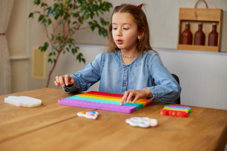 Little girl playing with big silicone popit, simple dimple, bubble fidget toy, antistress sensory toy at home. The concept of mental health popit toy