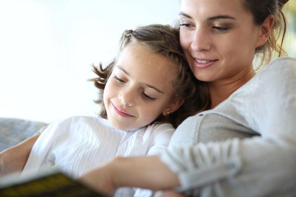 Mom and daughter reading book together