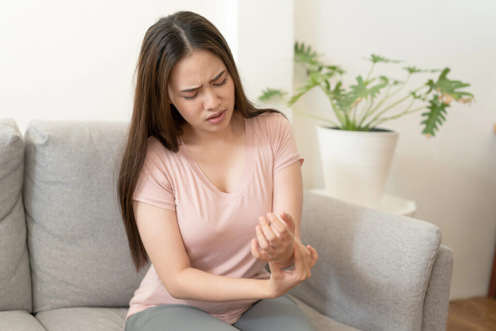 Asian girl having Wrist Pain sitting on sofa at home. young girl has pain arthritis
