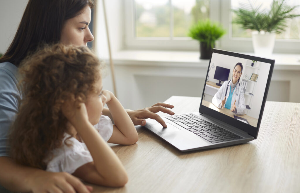 Healthy mother and child enjoying digital era, having online telemedicine consultation with remote doctor or watching educational video by professional paediatrician about cold and flu virus treatment