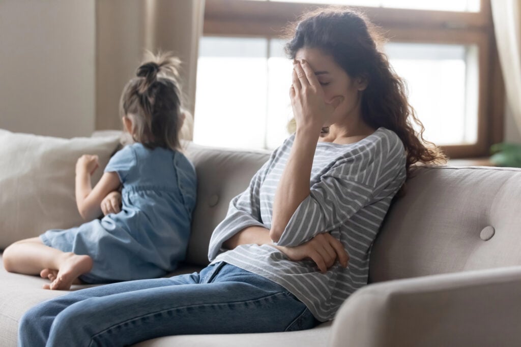 Unhappy mother touching forehead, feeling tired of bad daughters behavior.
