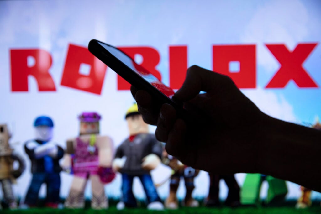 LONDON, UK - March 2021: Person holding a smartphone with Roblox game logo