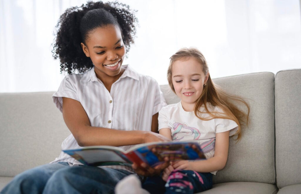 A nursery babysitter with five years old child girl reading story