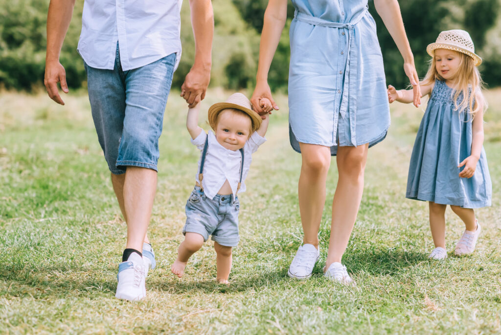 parents holding hands with children and walking on green feild together