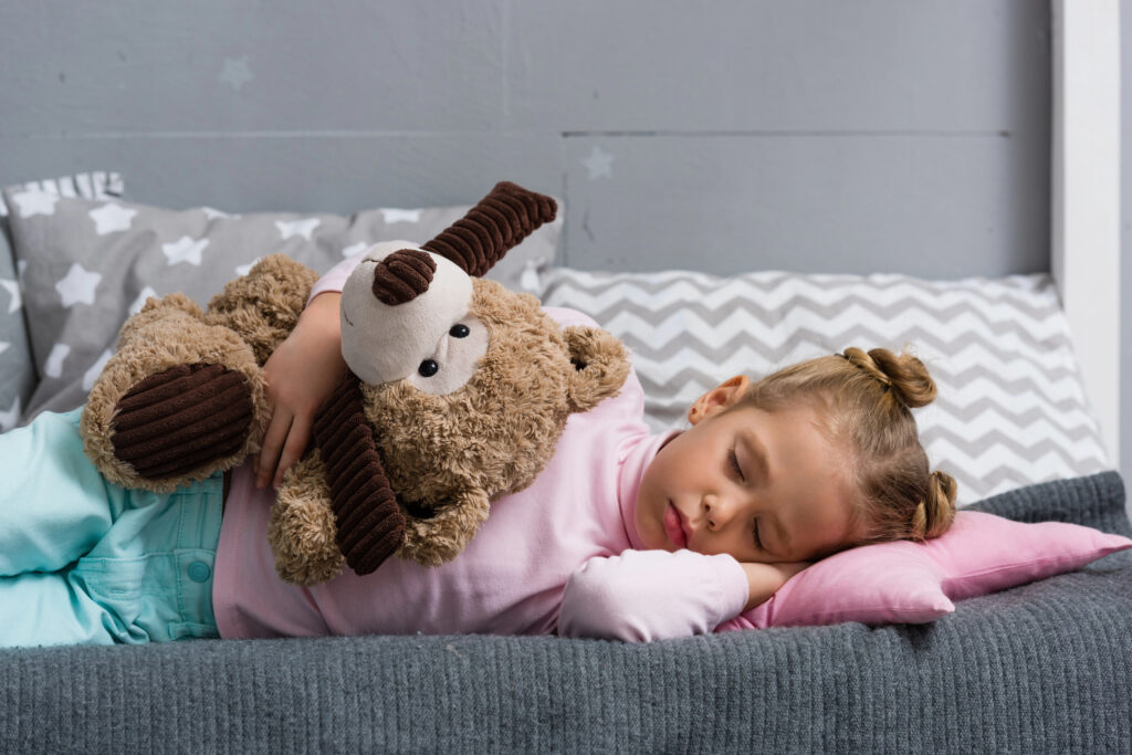 adorable little kid sleeping on couch with teddy bear