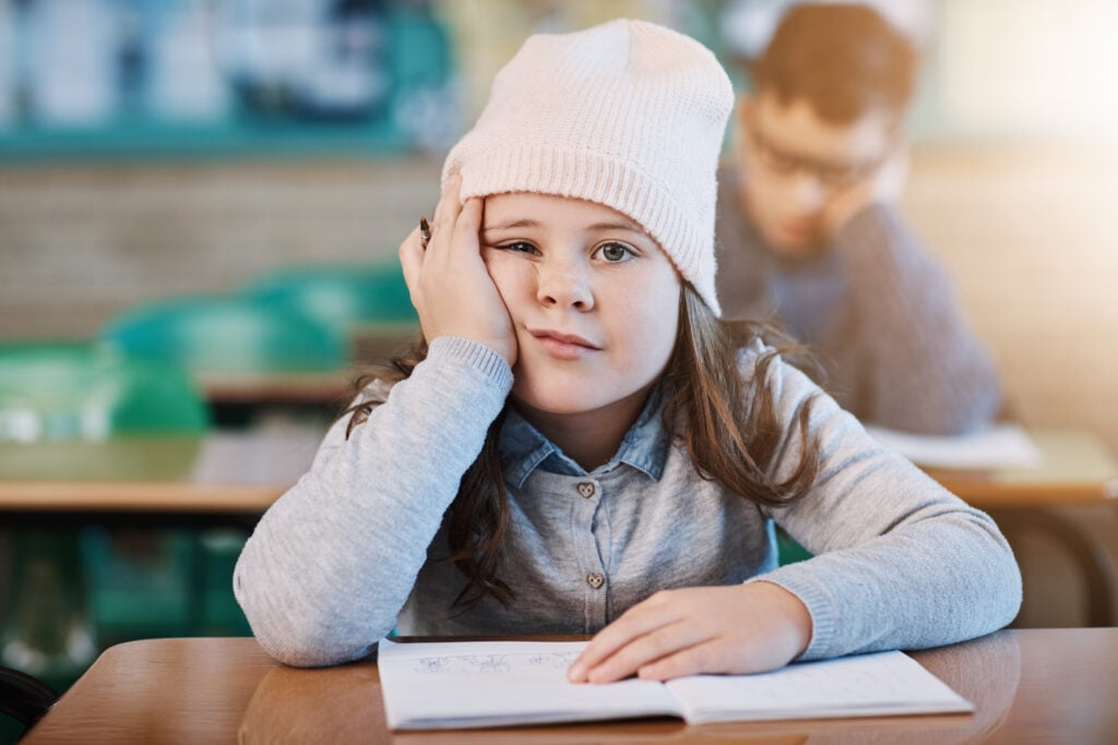 Bored, student and portrait of kid in classroom for education, learning and lazy. Child, fatigue and face of girl in elementary school with adhd, tired and burnout for creative drawing on notebook.