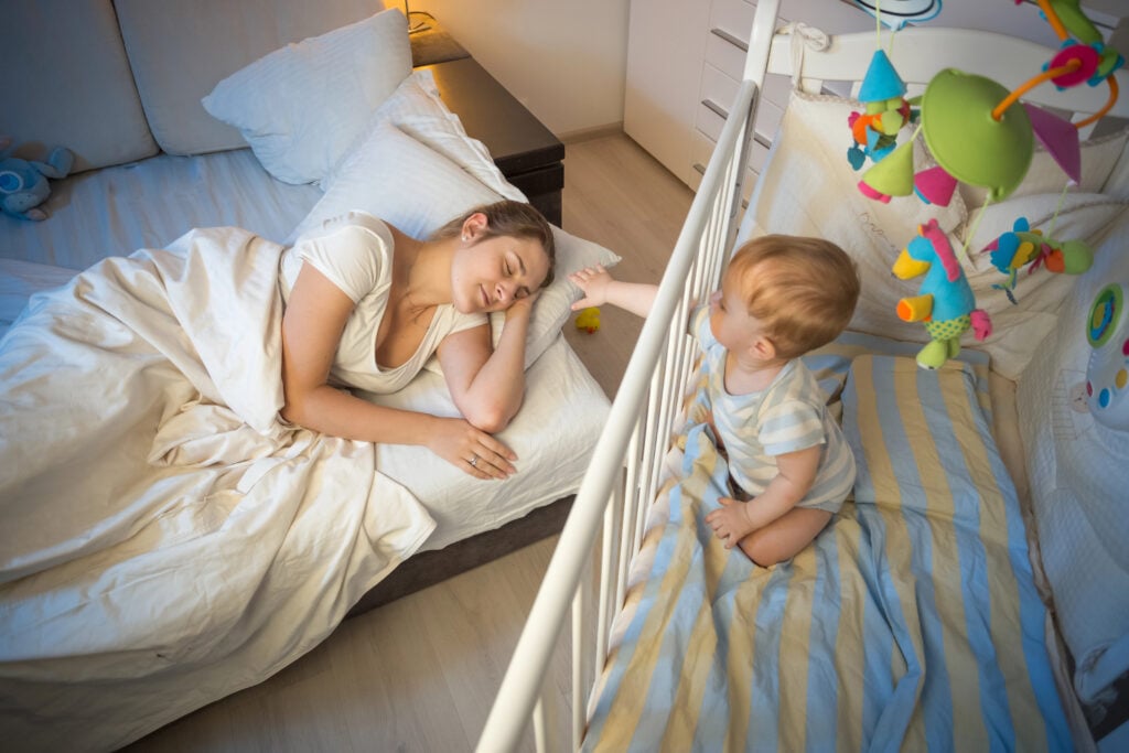 Crying baby waking up and reaching his mother at night