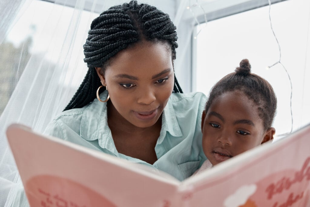 Home, girl and mother reading a book, relax and bonding together with happiness, learning and language. Development, family and single parent with child, mama and kid with fairytale and storytelling.