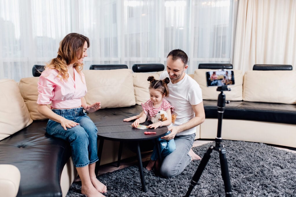 family blogger influencer recording video blog concept at smartphone on tripod at home. family social media vlogger shooting vlog, streaming online podcast on mobile phone