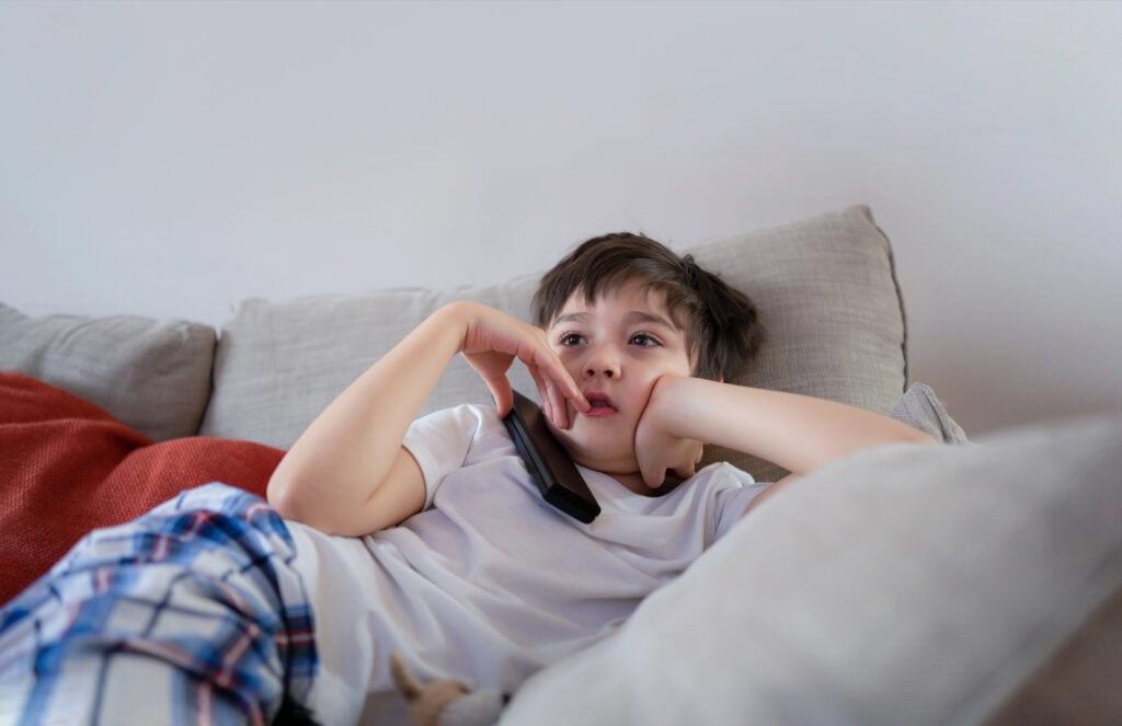 boy relaxing on sofa watching tv
