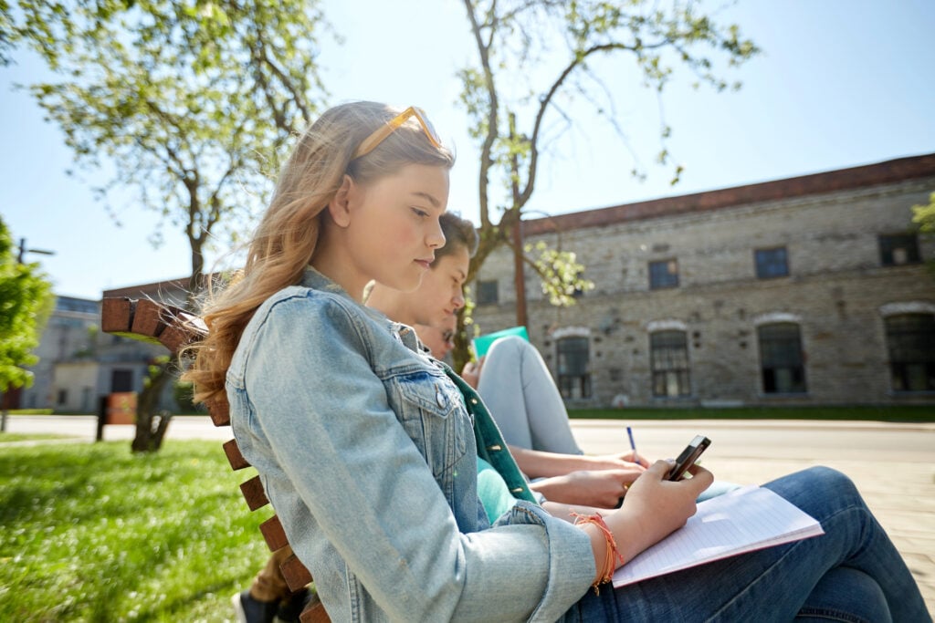 group of students with smartphone and notebooks